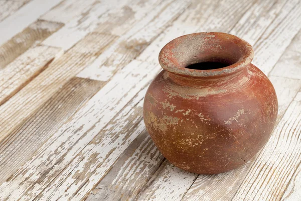 Red clay pot on rustic table — Stock Photo, Image