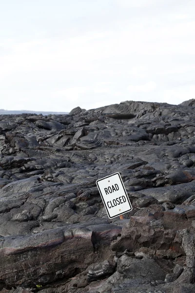 Дорога закрыта знак в окружении черной лавы — стоковое фото