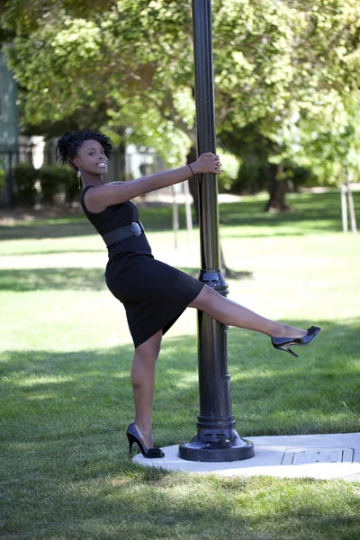Young black woman in dress holdig on to pole — Stock Photo, Image