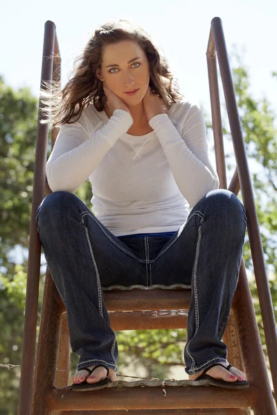 Молода жінка сидить зверху сходи джинси білий верх — стокове фото