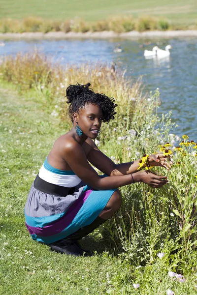 Μαύρη γυναίκα οκλαδόν από λουλούδια πάρκο — Φωτογραφία Αρχείου