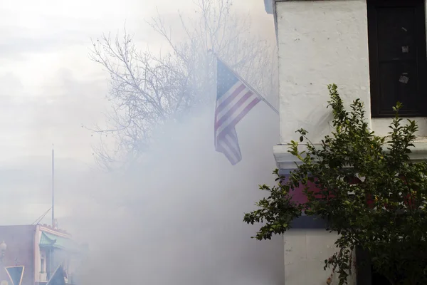 Smoke rising around building obscuring US Flag — Stock Photo, Image