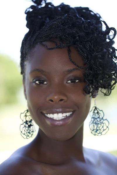 açık havada dikey genç bir Afrikalı-Amerikalı kadın gülümsüyor