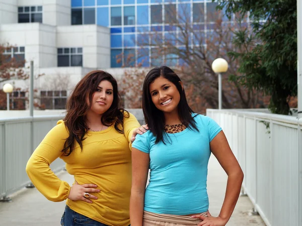 Две латиноамериканские сестры на открытом воздухе портрет стоящих зданий — стоковое фото