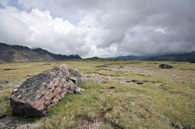 Highland pasture with stones against fog clouds clipart