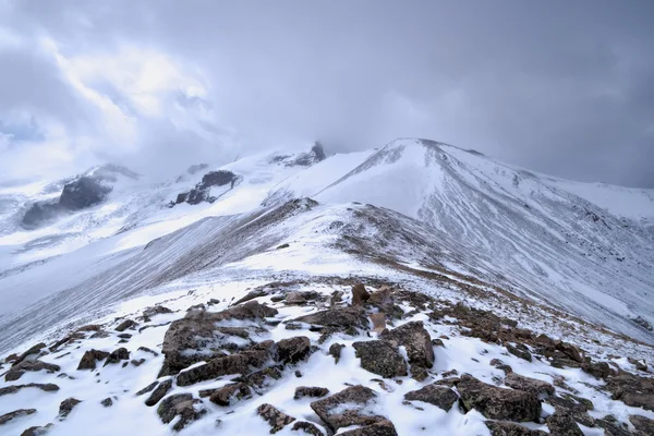 Klippiga bergslandskap med stenar och snö. Stockbild