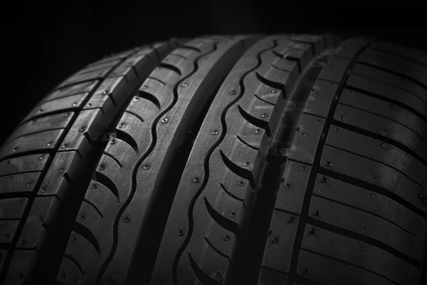 Neumático de coche sobre fondo negro —  Fotos de Stock