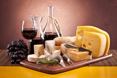 Cheese, wine and other tasty stuff on wooden table clipart