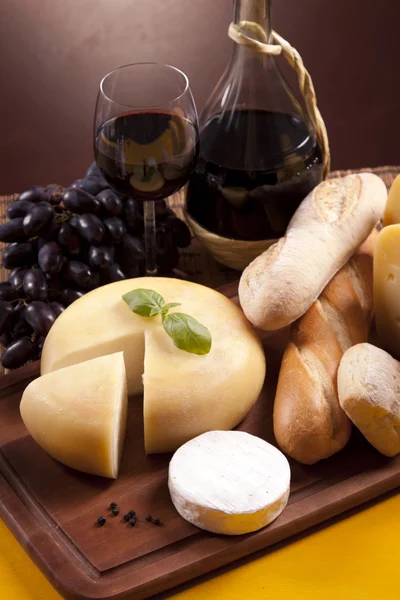 Queijo, vinho e outras coisas saborosas na mesa de madeira — Fotografia de Stock