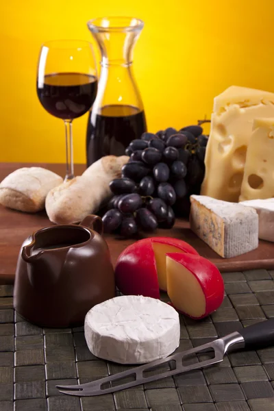 Cheese, wine and other tasty stuff on wooden table — Stock Photo, Image