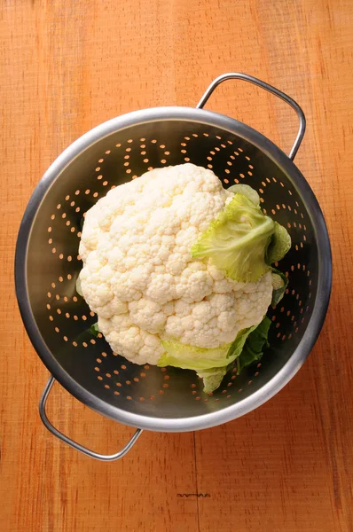Cauliflower in Colander on rustic wood table — Stock Photo, Image