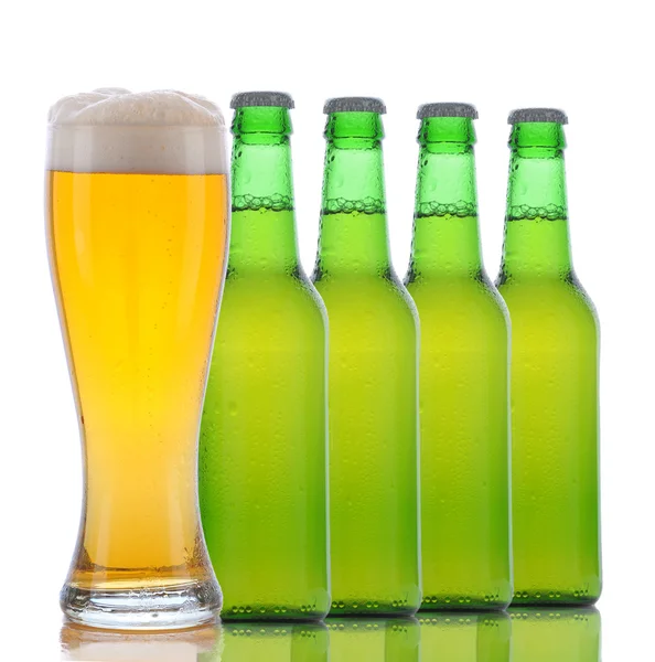 Quatro garrafas de cerveja e vidro completo — Fotografia de Stock