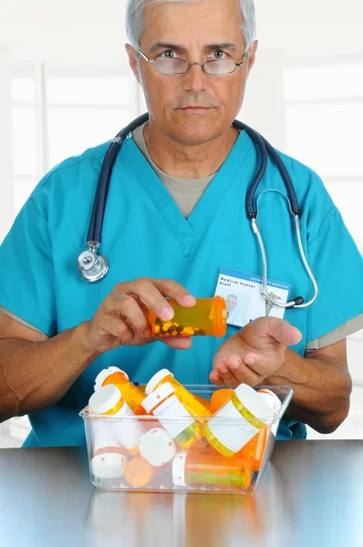Doutor derramando pílulas em sua mão — Fotografia de Stock