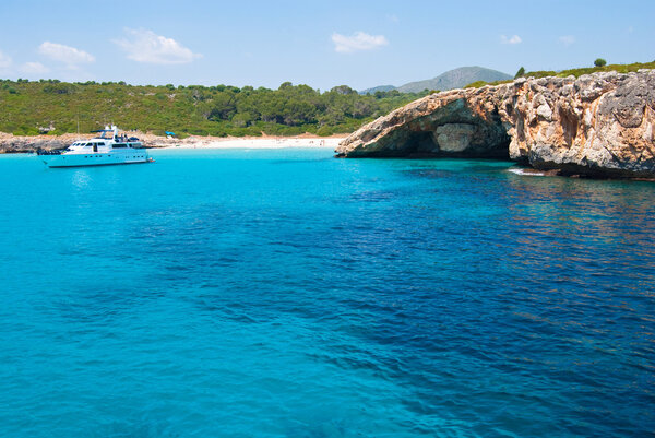 Speed boat in a quiet bay with beach and grotto, Majorca, Spain