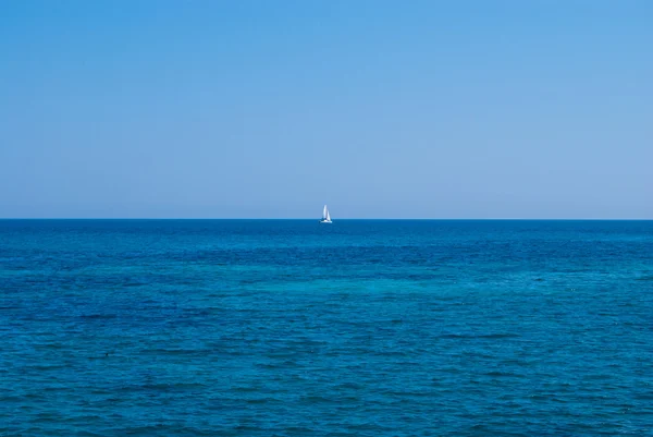 Ensam båten i ett öppet hav under solid blå himmel — Stockfoto