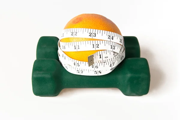 Grapefruit with measure tape on dumbbells — Stock Photo, Image