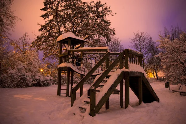 Speeltuin bedekt met sneeuw in de nacht op lange blootstelling — Stockfoto