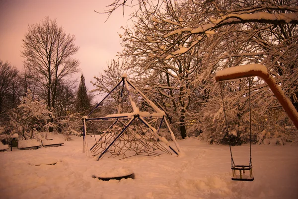 Swing covered in snow at night on long exposure — Stock Photo, Image