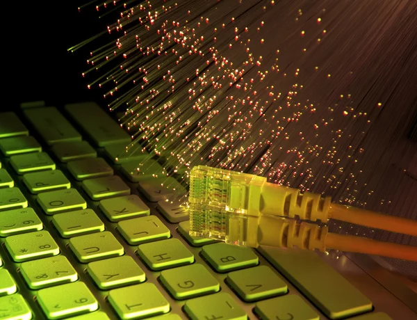 Fiber optics background with network cable on laptop keyboard — Stock Photo, Image
