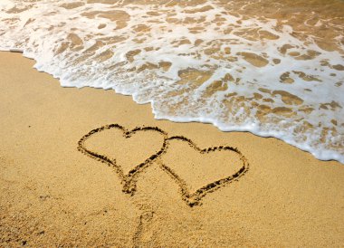 Two hearts drawn in beach in sunset clipart