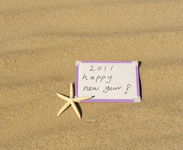 Feliz año nuevo mensaje en la playa de arena —  Fotos de Stock