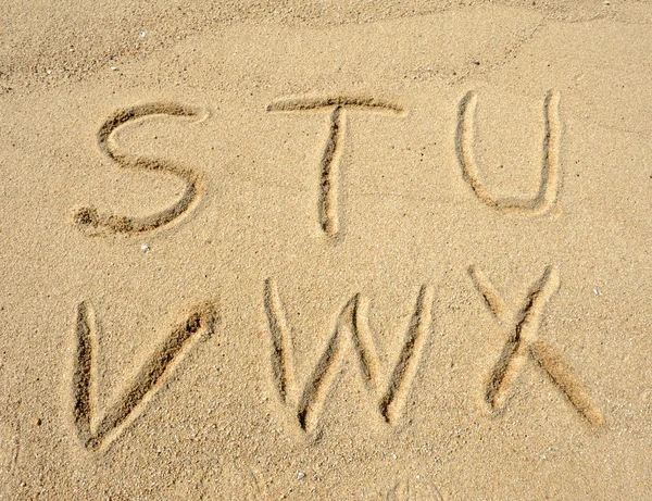 Bokstavene er håndskrevet i sand på stranda – stockfoto