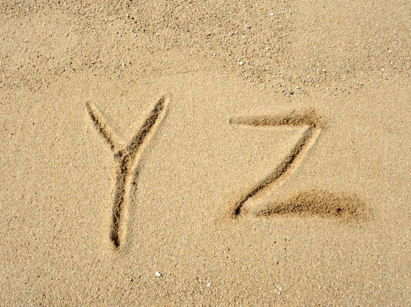 Alphabet letters handwritten in sand on beach — Stock Photo, Image