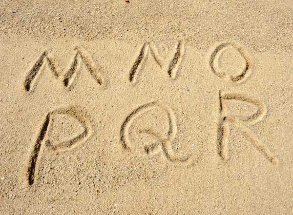 Letras del alfabeto escritas a mano en arena en la playa — Foto de Stock
