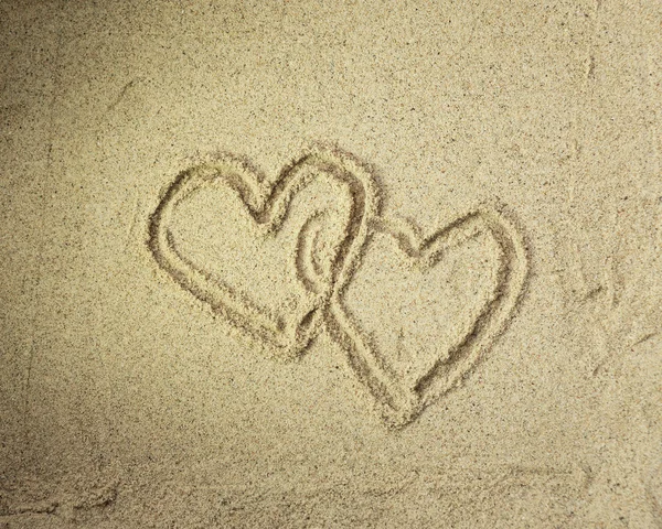 Dos corazones dibujados en la playa al atardecer — Foto de Stock