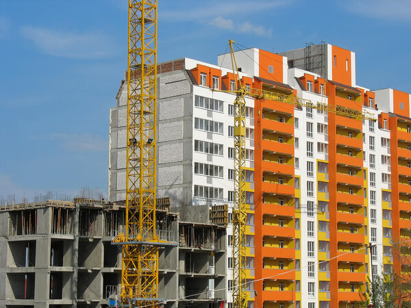 Construction of new modern apartments house and a crane over blue sky background