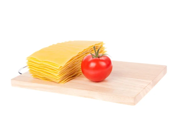 Pâtes lasagnes et tomates sur planche à découper — Photo