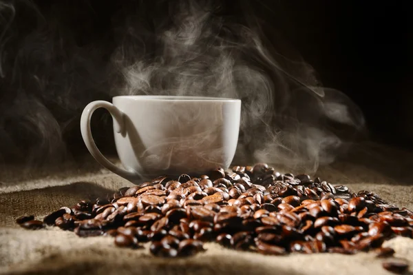 Кофейные бобы с кружкой на грубом мешке — стоковое фото