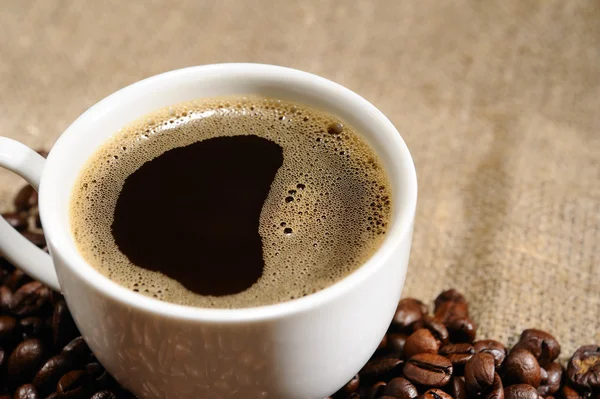 Granos de café con taza en un saqueo áspero — Foto de Stock