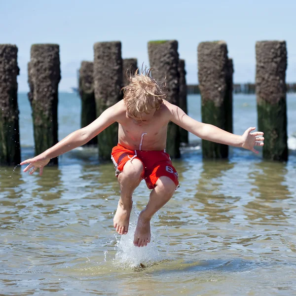Chłopiec skacze w morze — Zdjęcie stockowe
