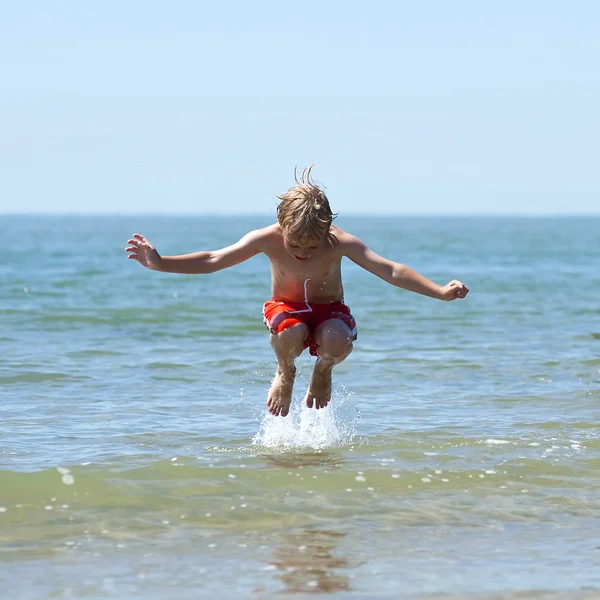 Хлопчик стрибає через хвилю — стокове фото