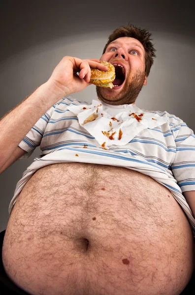 Gros homme manger un hamburger — Photo