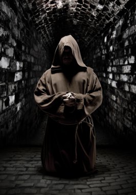 Praying monk in dark temple corridor clipart