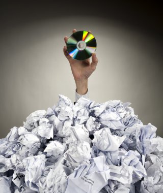 Hand with CD reaches out from heap of papers clipart