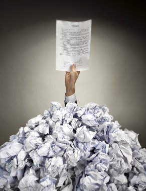 Hand with agreement reaches out from heap of papers