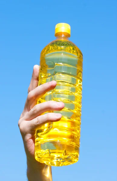 Hand som håller flaskan solrosolja — Stockfoto
