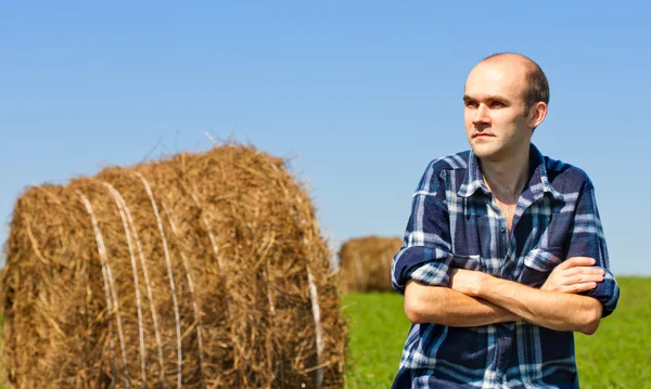 Farmář v poli proti pšenice balíků — Stock fotografie