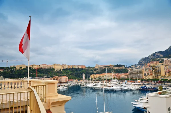 The flag of Monaco and Monte Carlo harbor in the background — Stock Photo, Image