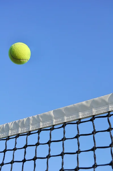 Желтый теннисный мяч пролетел над сетью — стоковое фото