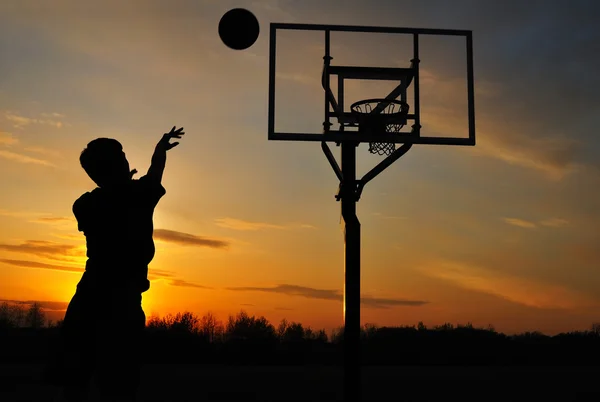 Sylwetka teen chłopiec strzelanie koszykówki — Zdjęcie stockowe