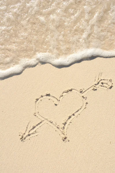 Coração com seta desenhada em areia na praia — Fotografia de Stock