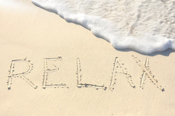 Relaks napisał w piasku na plaży — Zdjęcie stockowe