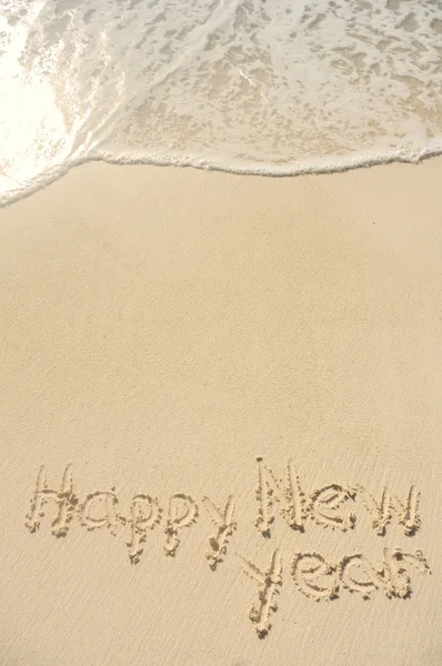 Feliz año nuevo escrito en arena en la playa — Foto de Stock