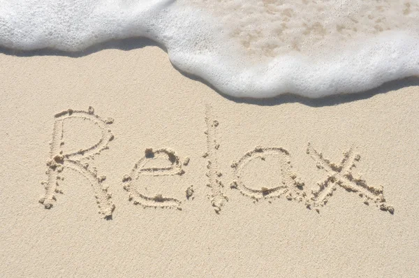 Relaks napisał w piasku na plaży — Zdjęcie stockowe