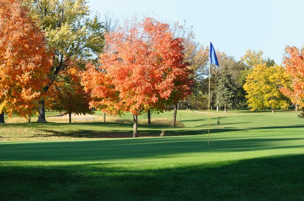 Golf zelených a flagstick s barevný podzim listí — Stock fotografie
