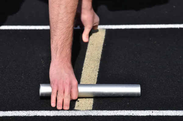 Hand som håller en stafettpinne på startlinjen — Stockfoto
